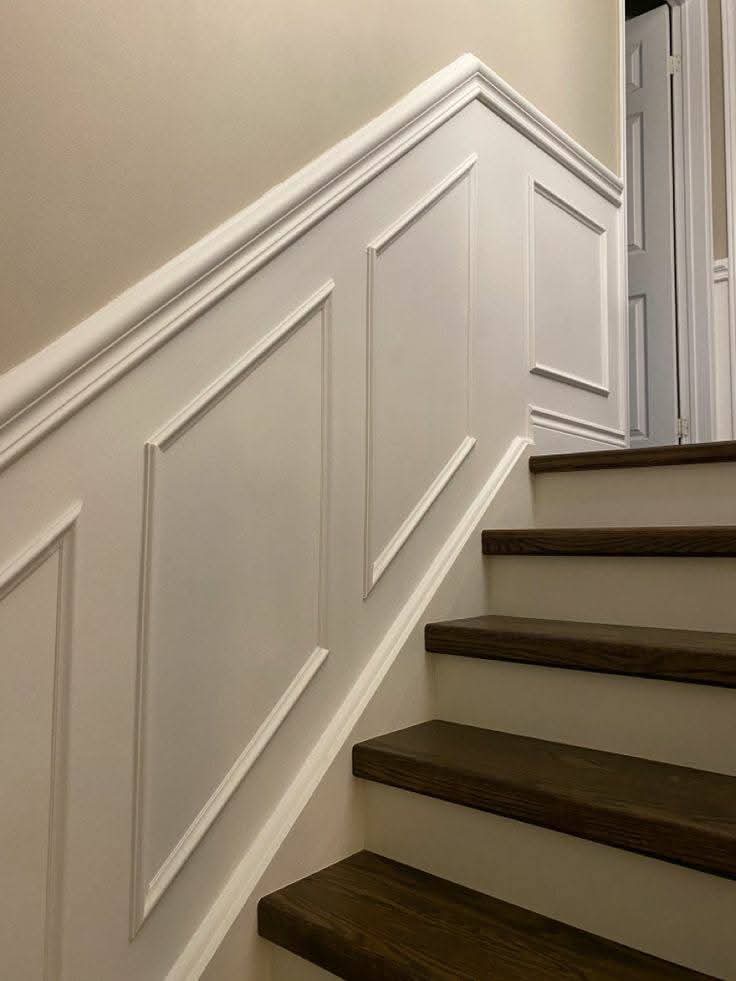 Elegant staircase with sophisticated wainscoting details by AGGY WALLS & INTERIORS